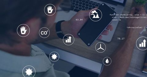 Holding phone scanning data overlays on workspace laptop for business analytics dashboard