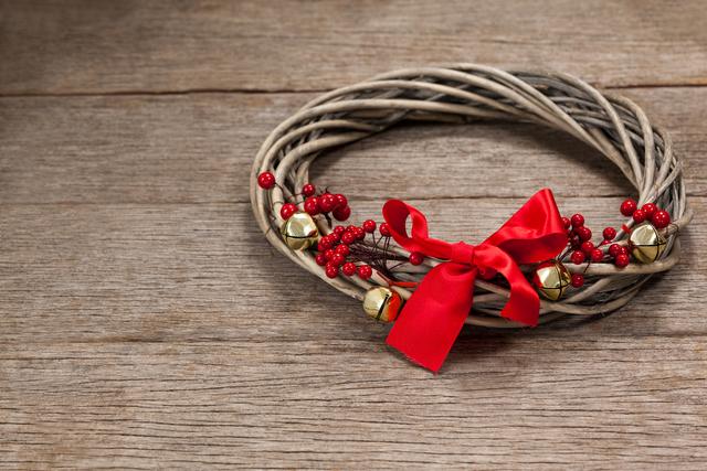 Grapevine wreath with red ribbon on a plank