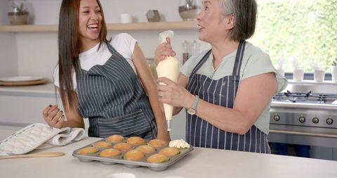 Asian Grandmother and Granddaughter Baking Together and Laughing