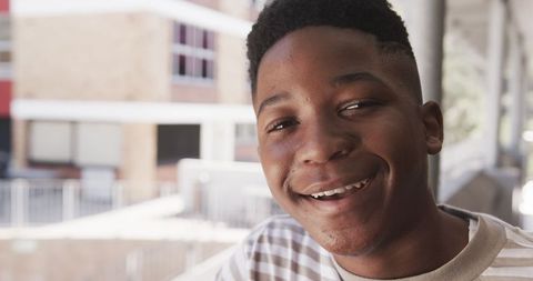 Smiling Teen Boy on Urban Walkway with Architectural Blur at Back