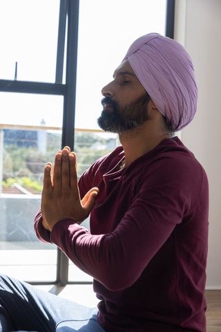Turbaned man practicing morning meditation by sunny window