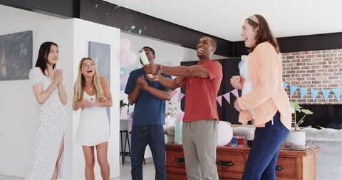 Joyous Friends Celebrating Baby Shower with Confetti in a Bright Room