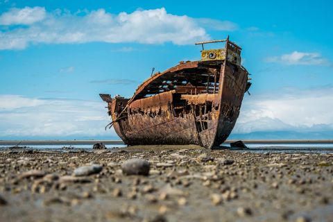 Rusty shipwreck on beach with blue horizon