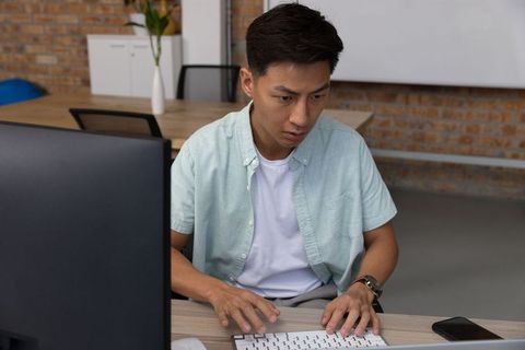 Focused businessman typing at desk in modern office environment