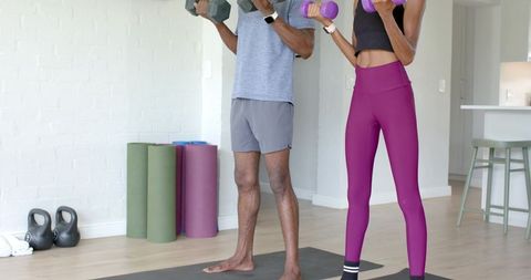 African american duo working out at home lifting dumbbells in open-plan living room