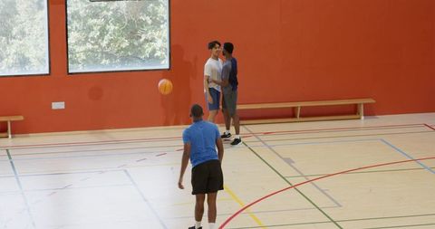 Three men passing basketball on indoor hardwood court casual teamwork and training
