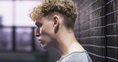 Man Resting Post-Workout Against Urban Fence Background