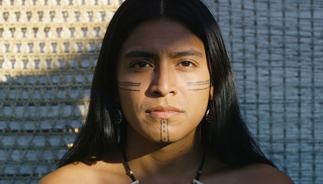 Sunlit portrait of man with traditional facial markings wearing beaded necklace