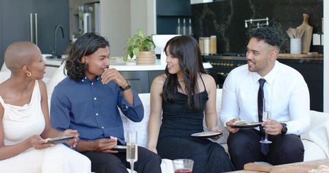 Friends chatting on sofa during stylish open-plan kitchen cocktail gathering