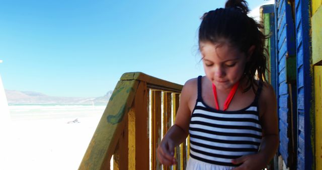 Young Girl Enjoying Sunny Day on Beach with Colorful Cabin - Download Free Stock Images Pikwizard.com