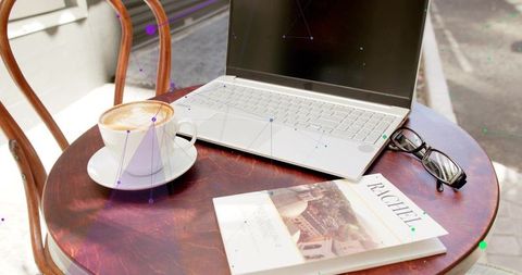 Outdoor Laptop Workspace at Café with Coffee and Travel Guide