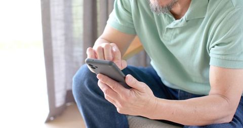 Senior man relaxing with smartphone in minimalist living space