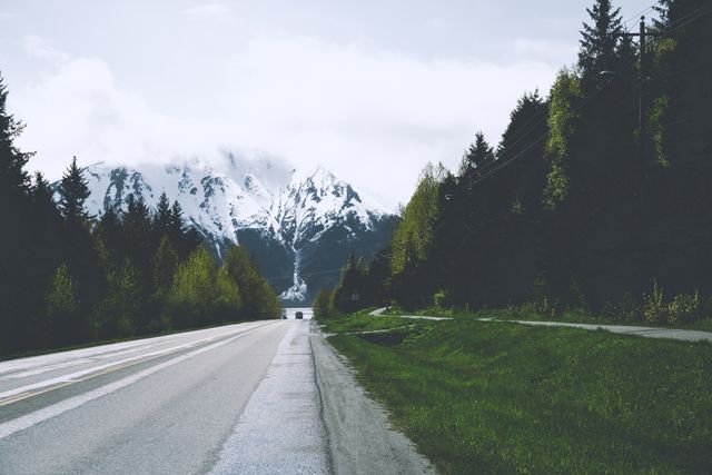 Empty Mountain Road with Snow-Capped Peaks and Lush Forests - Download Free Stock Photos Pikwizard.com