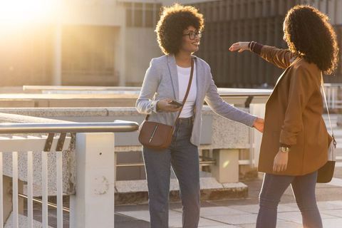 African american women greeting on rooftop terrace during golden hour business meetup