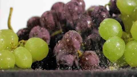 Fresh Yellow and Purple Grapes Dripping with Water in Slow Motion