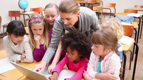 Engaged Teacher Using Laptop in Classroom with Enthusiastic Students