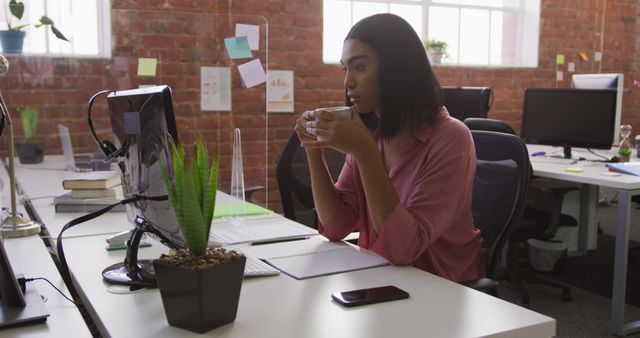 Focused Young Woman Drinking Coffee at Workstation in Bright Modern Office - Download Free Stock Images Pikwizard.com