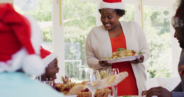 Family members wearing Santa hats enjoying festive Christmas dinner with roast chicken. Perfect for holiday-themed promotions, family gatherings, festive greetings cards, or advertisements showcasing joyful holiday moments.