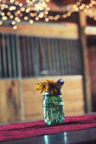 Rustic mason jar centerpiece with wildflowers in barn setting