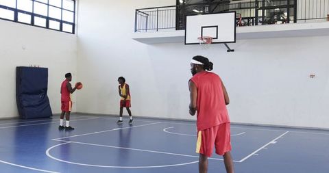 Energetic Basketball Players Practicing Indoors on a Court