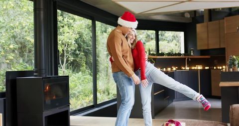 Couple Sharing Festive Hug in Modern Open-Plan Home with Wood-Burning Stove and Gifts