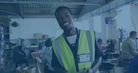 Smiling worker holding tablet in a busy workshop environment