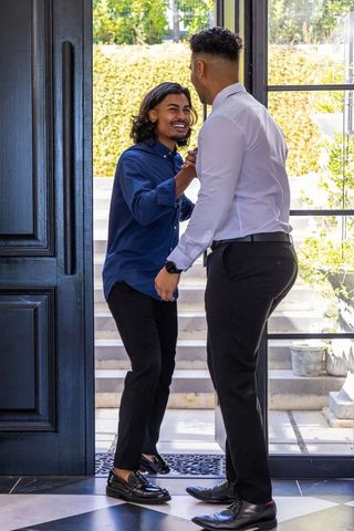 African american men greeting at residential entryway, sharing warm handshake and smiles