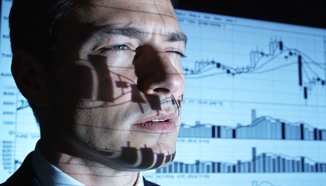 Businessman studying projected financial charts with candlestick graphs and focused gaze