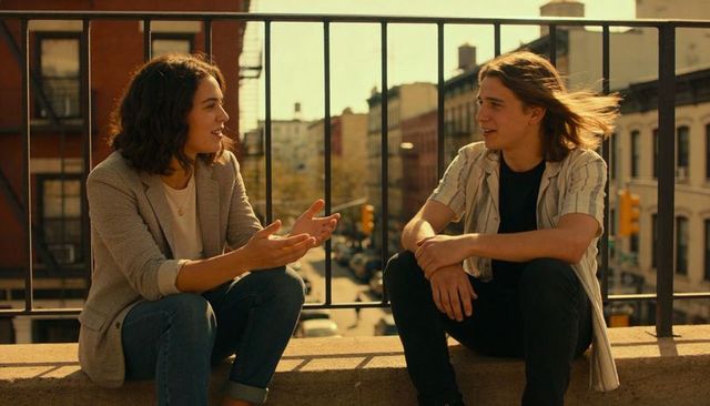 Sunlit rooftop conversation between young friends on urban ledge during golden hour