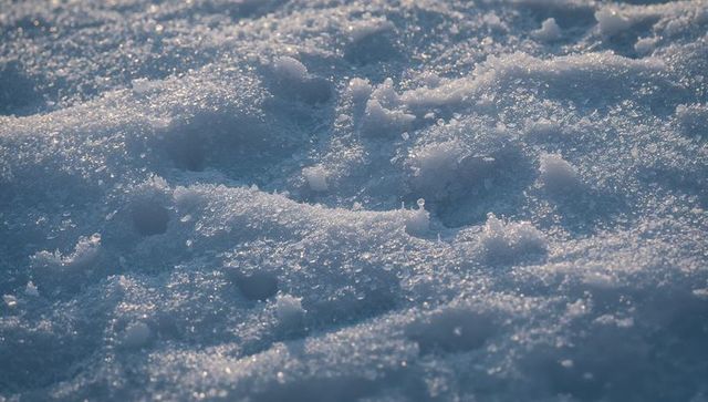 Sparkling snow crystals and frosty mounds catching low sunlight on frozen field