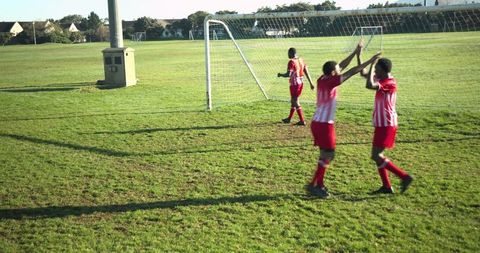 Youth soccer team celebrating goal on field outdoors