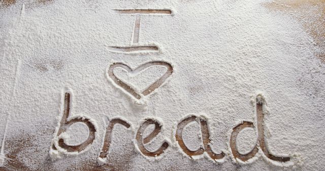 Floured wooden surface with 'I love bread' text artfully written. Ideal for bakery ads, cooking blogs, or culinary-themed promotions.