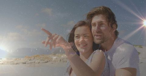 Couple Embracing on Tranquil Sunset Beach Pointing Towards Horizon