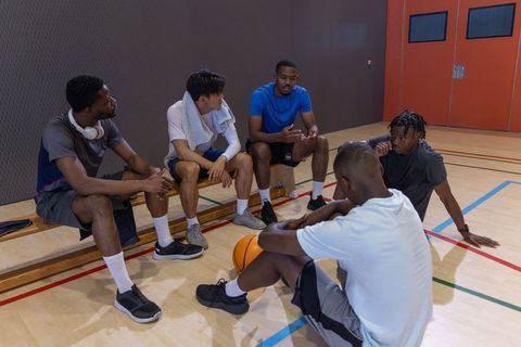Multiracial basketball teammates discussing strategy during timeout on indoor court
