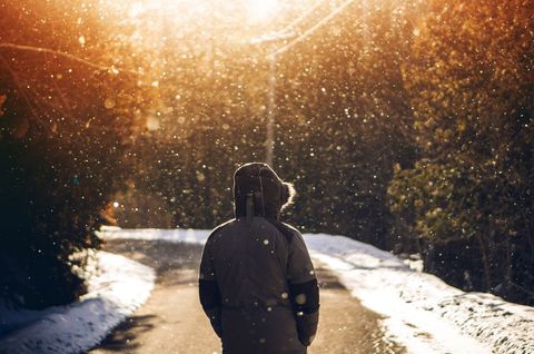 Person walking alone on sunlit winter road