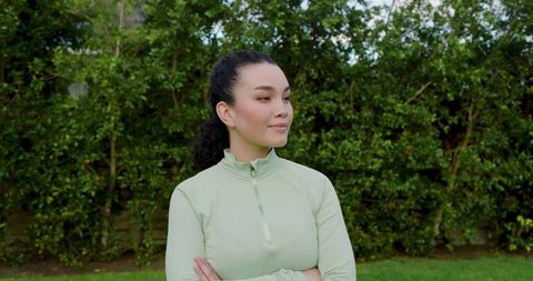 Confident Woman in Green Athletic Wear Standing in Garden