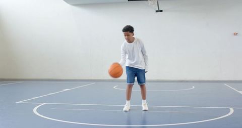 Youth Practicing Basketball Skills on Indoor Court