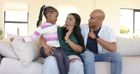 African american family sharing joyful moment with daughter sitting on mother's lap on sofa