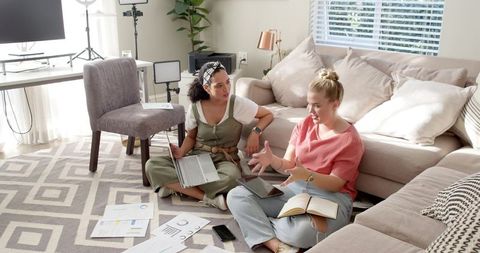 Diverse female friends collaborating on charts with laptop