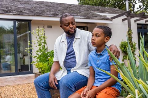 African american father comforting son on backyard bench showing emotional support and bond