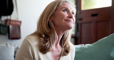 Serene Senior Woman Relaxing on Sofa at Home with Soft Smiling Expression