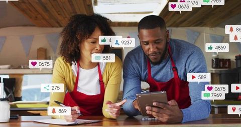 Entrepreneurs reviewing social media metrics on tablet at rustic market stall