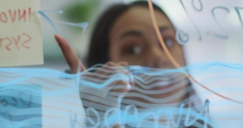 Businesswoman pointing at glass board during team brainstorming and planning