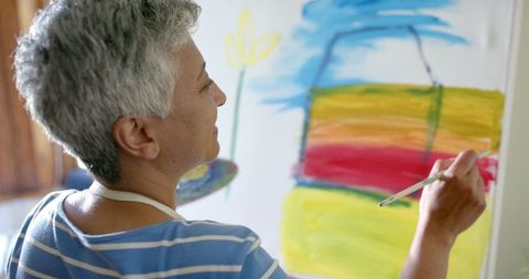 Senior Woman Engaged in Colorful Canvas Painting at Home