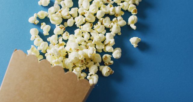 Close-Up Overflowing Popcorn Box on Blue Background with Copy Space - Download Free Stock Images Pikwizard.com