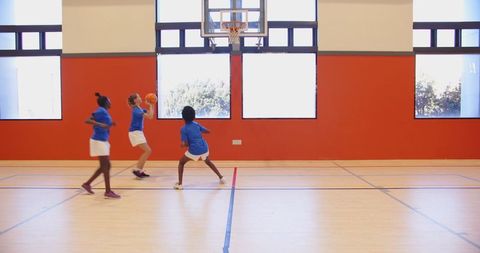 Female Child Athletes Practicing Basketball in Gymnasium