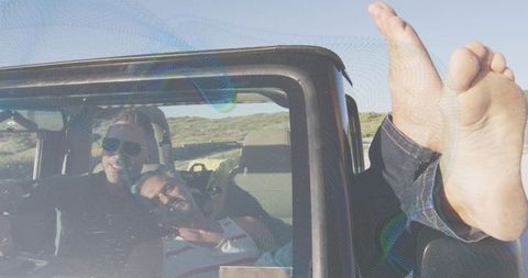 Carefree jeep road trip with sunglasses driver and barefoot passenger relaxing on scrubland