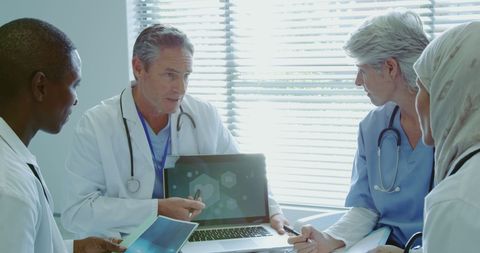 Multicultural Medical Team Collaborating with Laptop in Modern Clinic