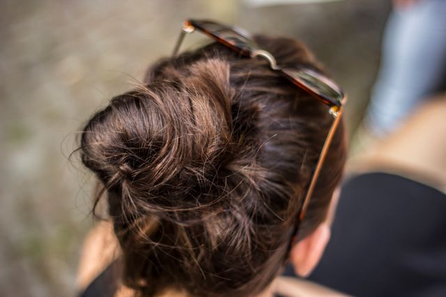 View focuses on a stylish messy bun adorned with sunglasses resting on top of the head. Can be used in fashion blogs, hairstyling tutorials, or lifestyle articles aiming at casual and elegant hair accessories.