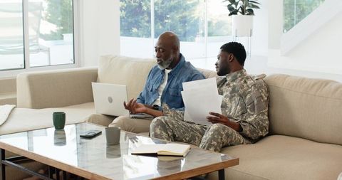 Father and son discussing documents at home with laptop collaboration